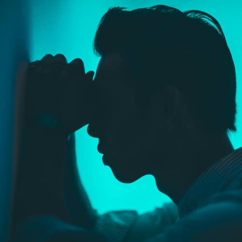 Photo de la silhouette d'un homme la tête posée contre un mur