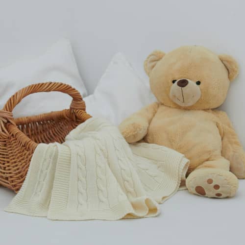 Photo d'un panier vide, une couverture de bébé, et un ours en peluche