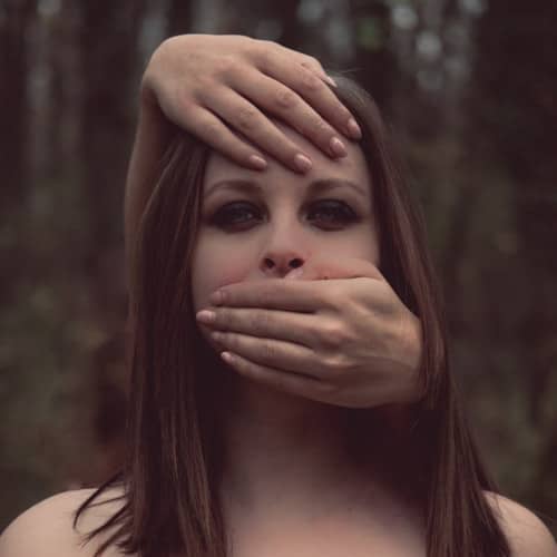 Photo d'une femme avec deux mains féminines lui barrant la bouche